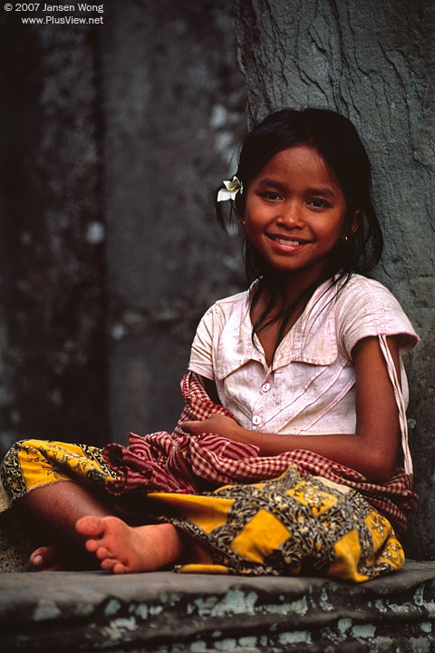 Smiling girl sitting on the rock window of Bayon Temple, Cambodia