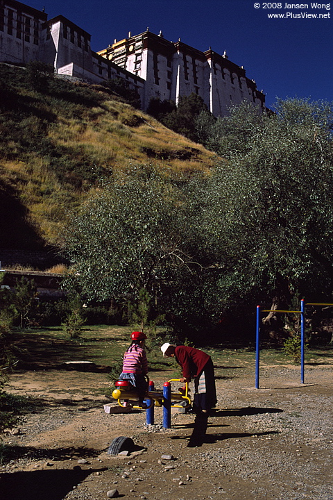 在布达拉宫背后的宗角禄康公园玩跷跷板的母女