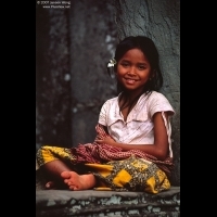 Smiling girl sitting on the rock window of Bayon, Siem Reap